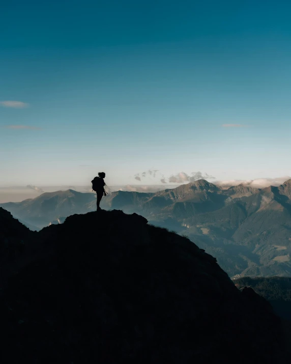 a lone man standing on the top of a mountain