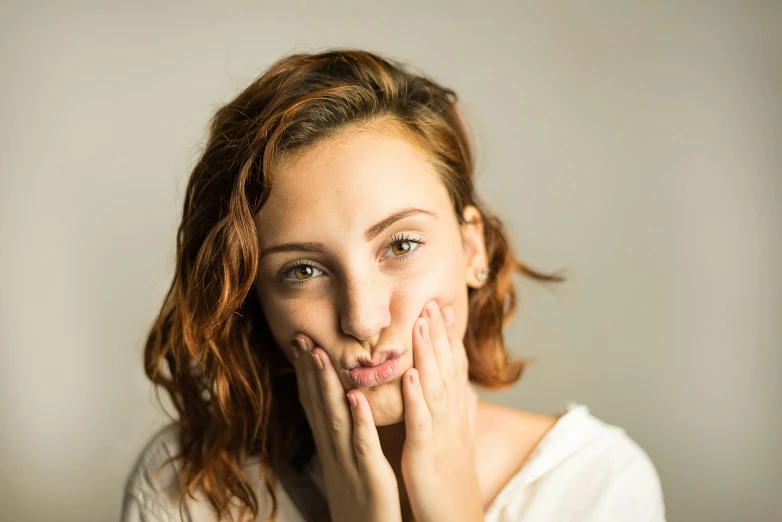 a woman is posing with her hands behind her face