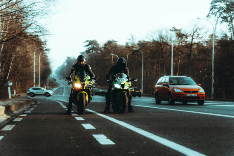 two people on motorcycles on a street with cars and people