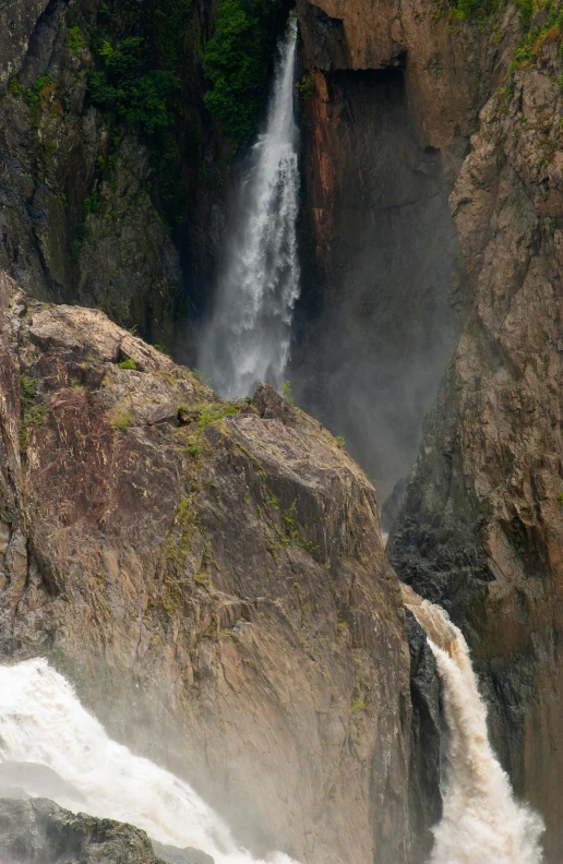 water falling over rocks into a stream near a forest