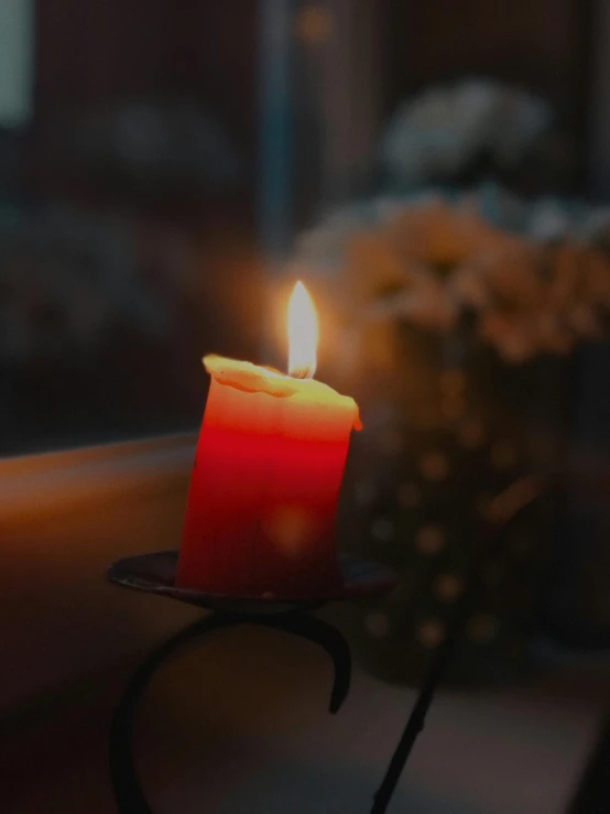 a red candle in front of flowers