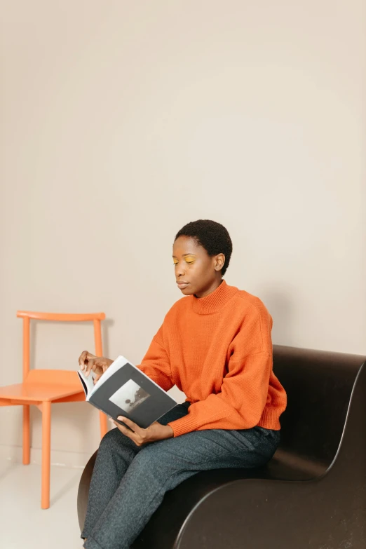 a young woman sitting on a chair holding a book