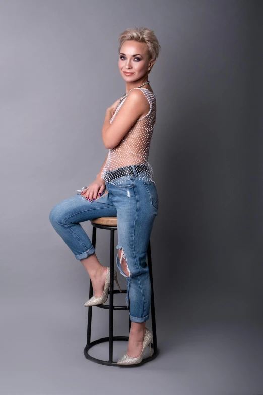 a woman sitting on top of a stool in jeans