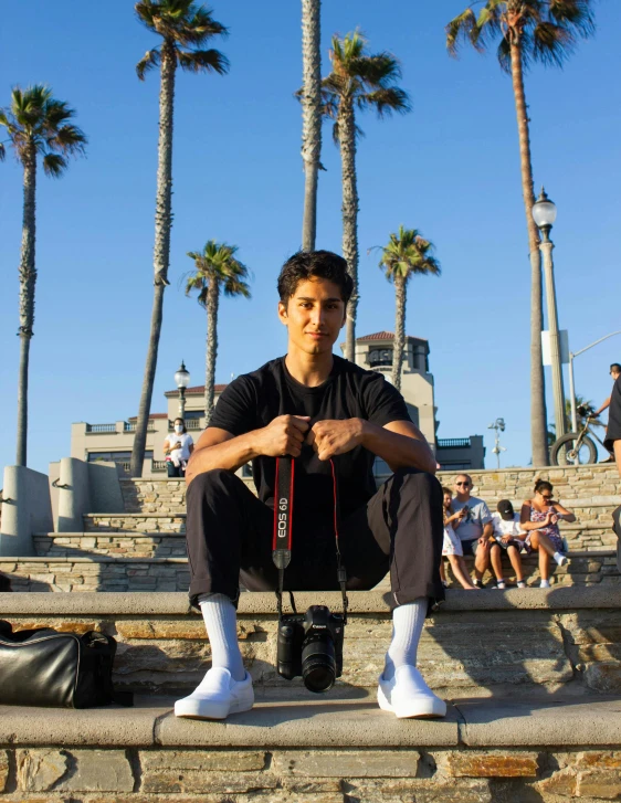 a man sits on steps while holding a camera