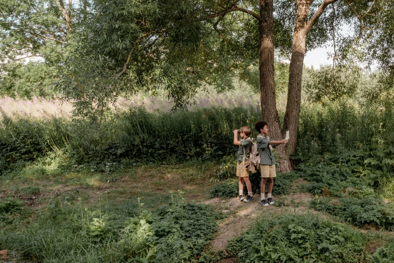 people standing next to a tree by some tall grass