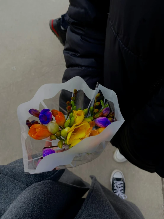 a person holding out colorful flowers in their hand