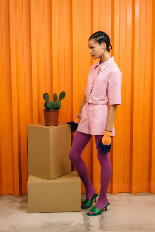 woman in pink standing near a box with cactus plant on it