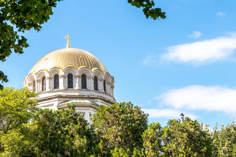 the white building has gold roof and a cross on top