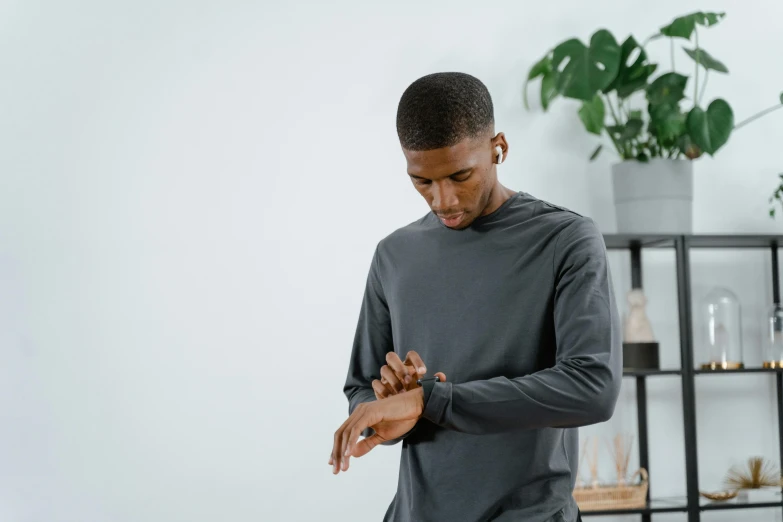 a man looking down at his hands in front of a plant