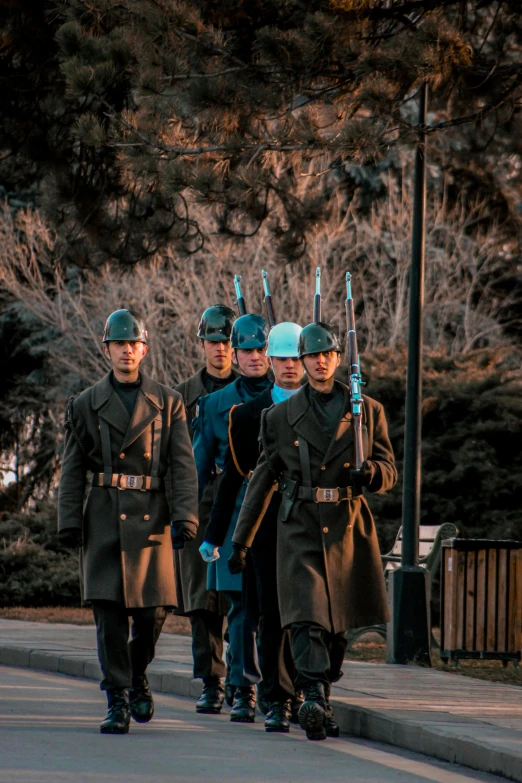 three men dressed in uniform walk down the street