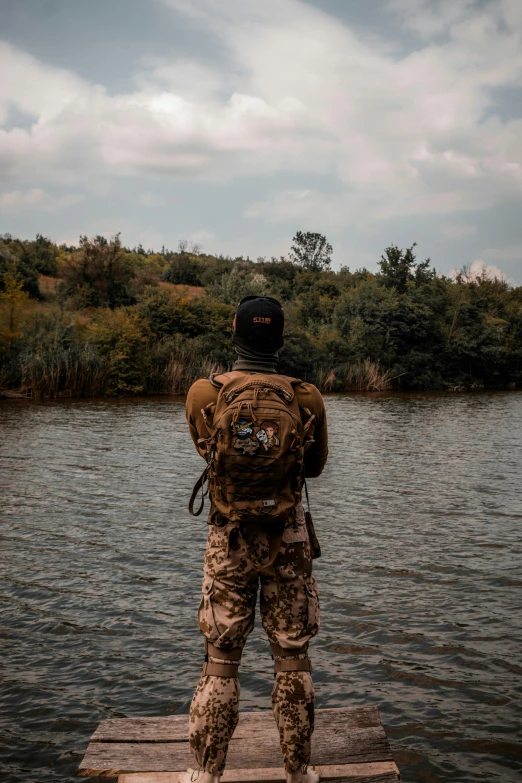 a man on a dock in military gear looking over water