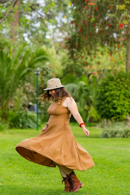 a woman walking in the grass in a dress and hat