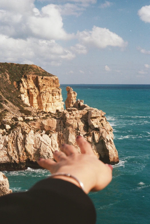 a person holds their hand up above the water