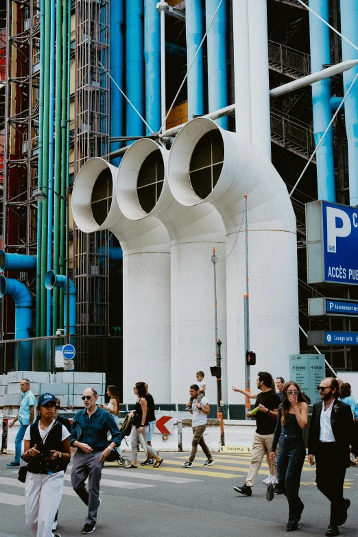 various people walking across a street with giant white sculptures on the building