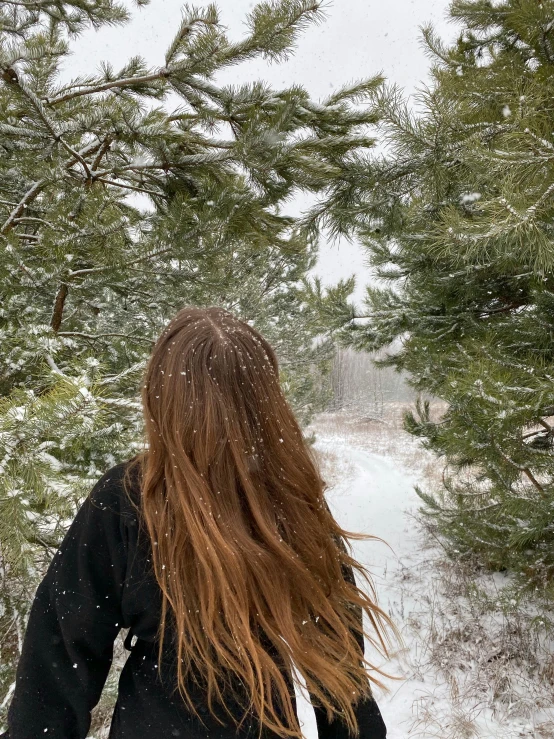 a woman standing in the snow with her hair blowing in the wind