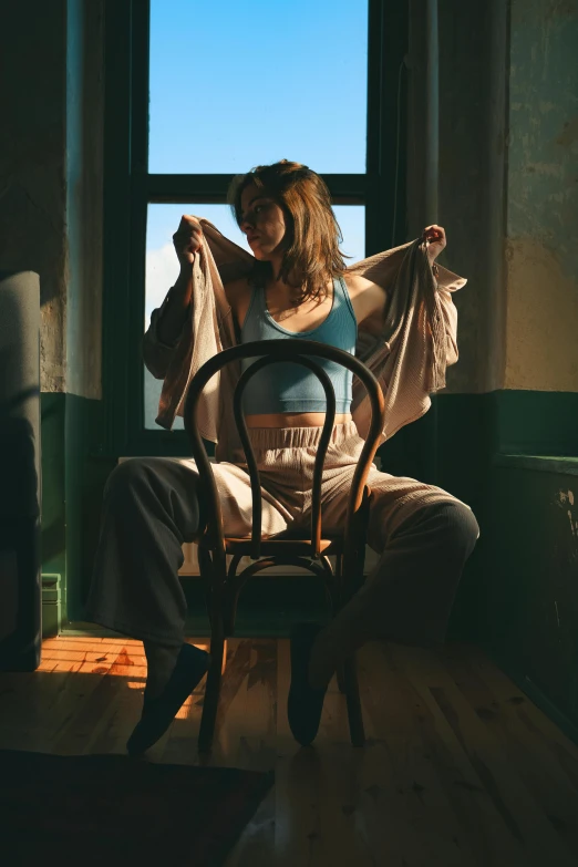 a woman in a room holds onto clothes by the window