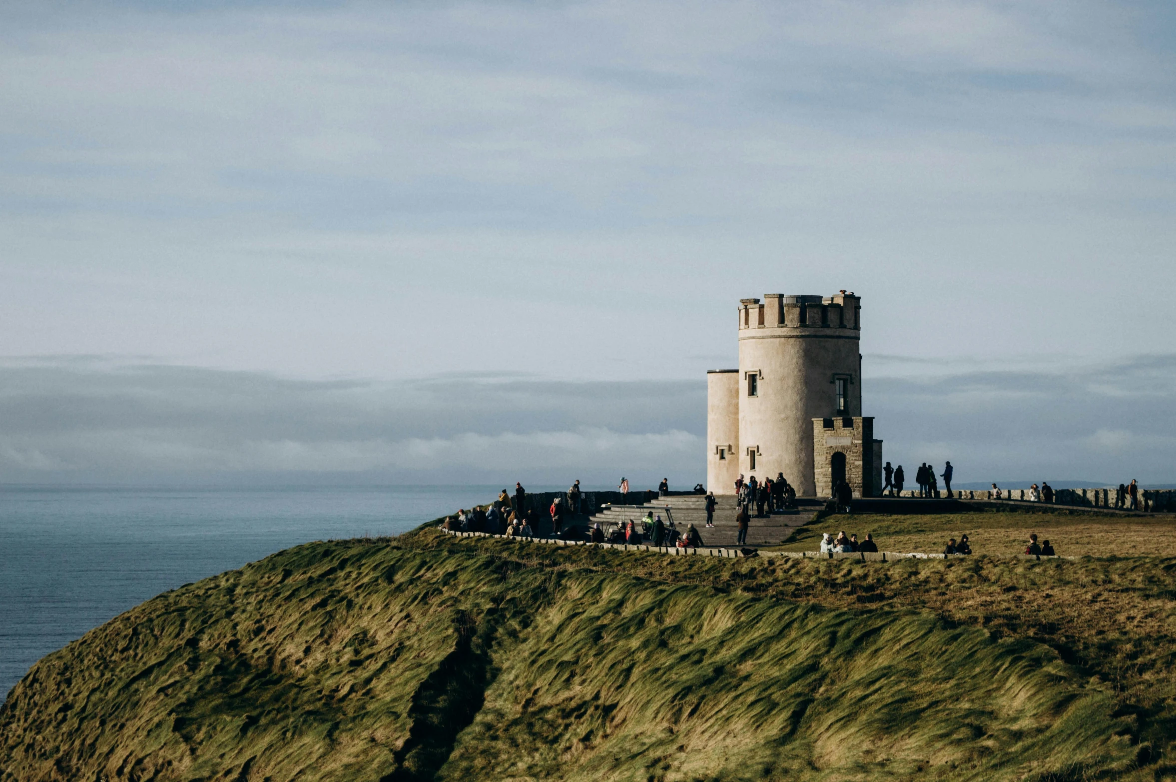 people standing at the base of an overhanged tower overlooking the water