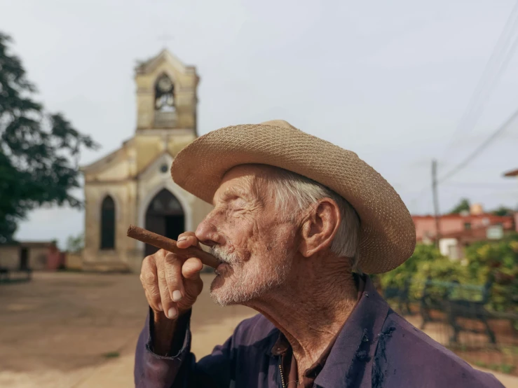 an older man smoking a cigar next to an old building