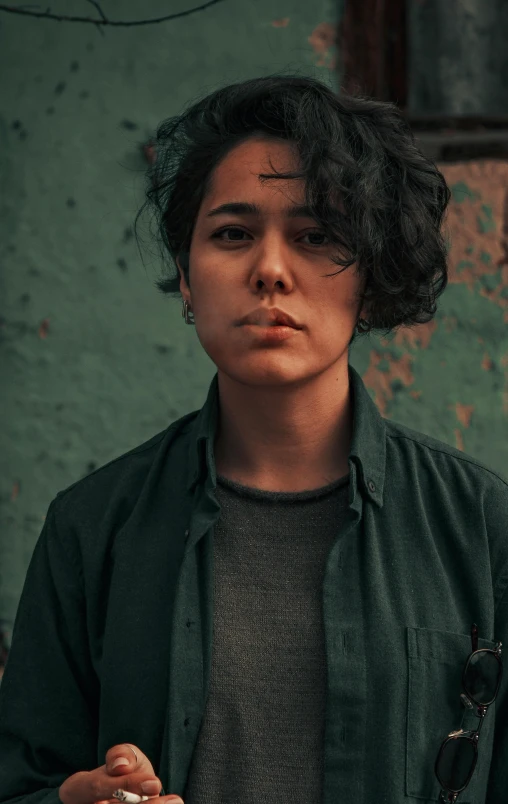 a woman with curly hair holding a cigarette in her hand