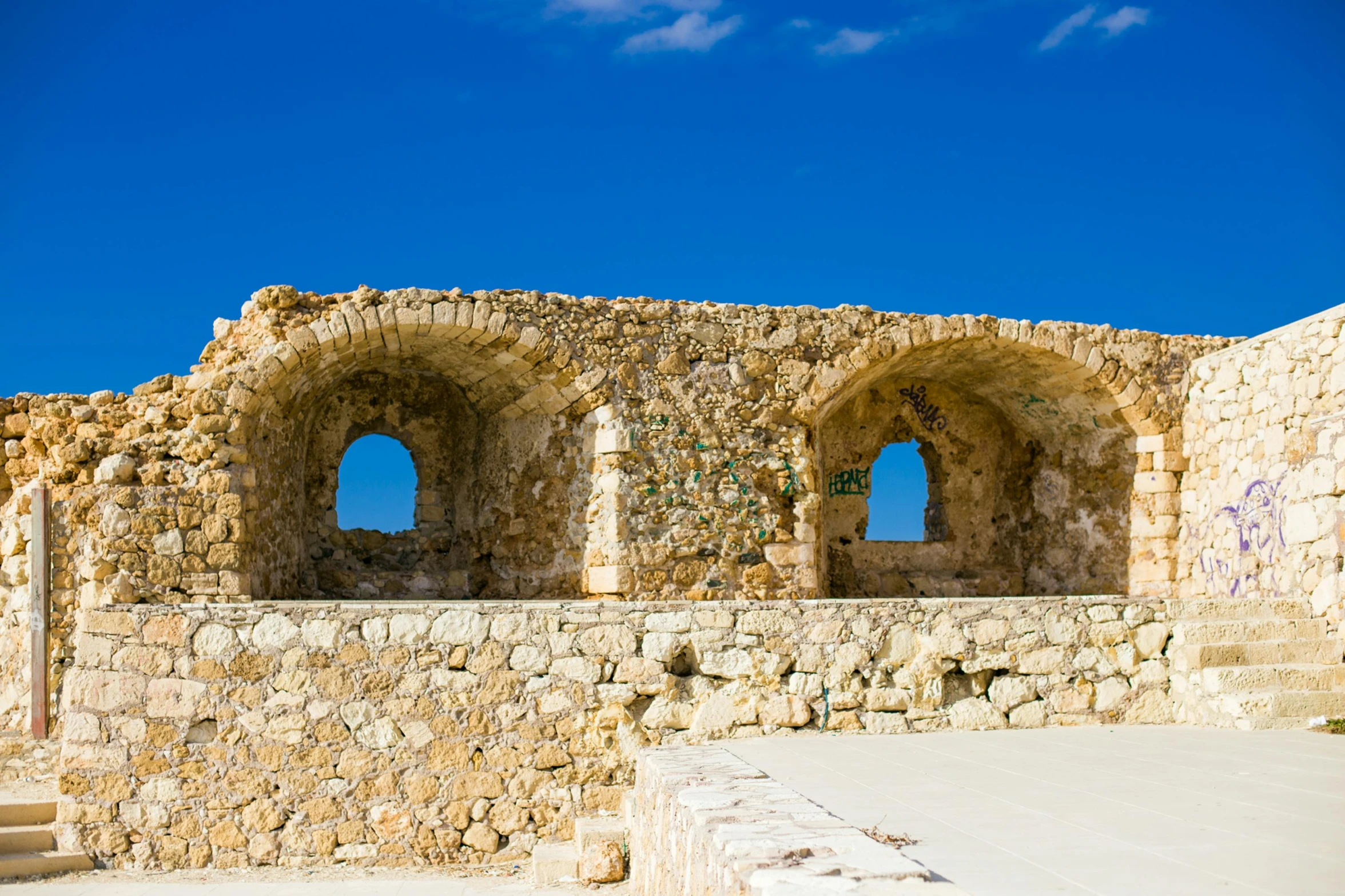 a stone building with three windows and graffiti written on it