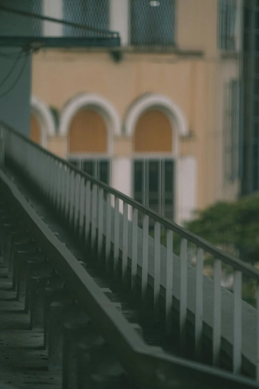 a long train is traveling past a building with arched windows