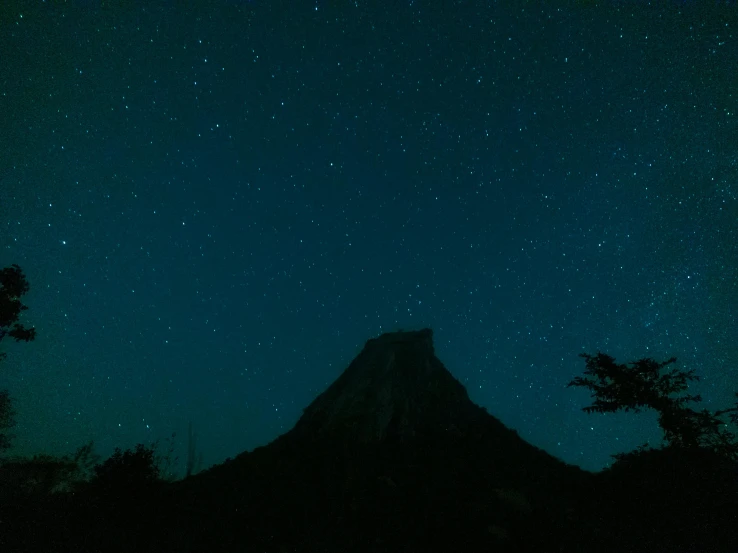 the mountain is covered in snow at night with stars overhead