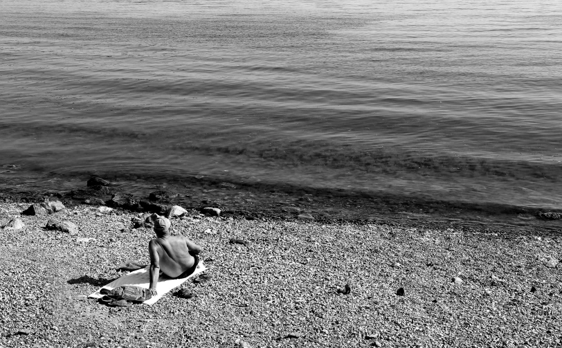 a woman sitting on the beach, in front of an ocean and water