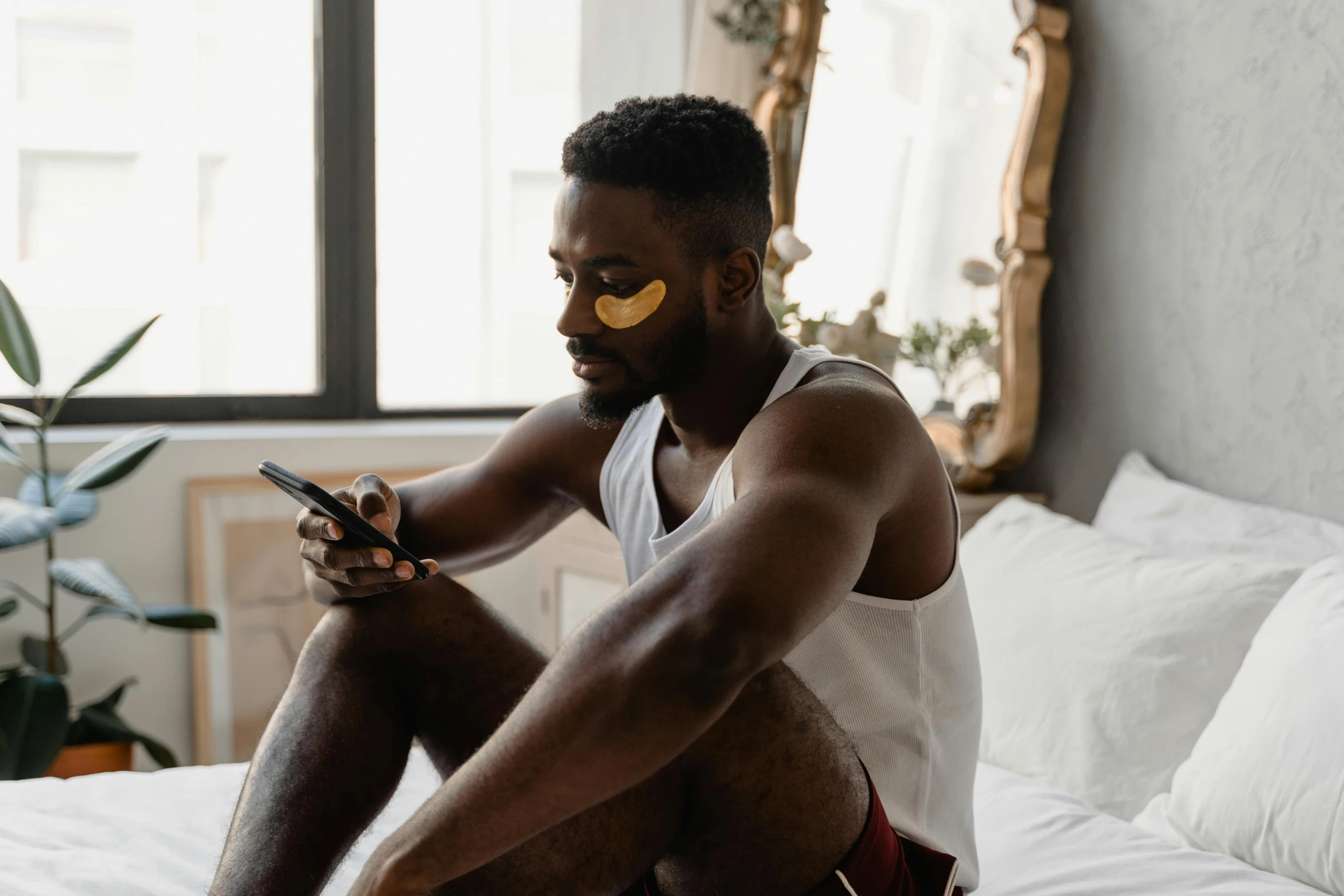 a man sitting on his bed using a phone