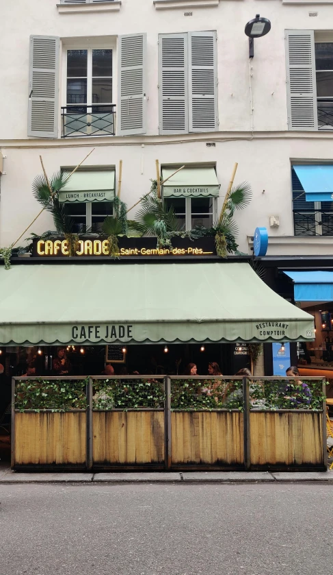 a cafe with white awnings and several plants