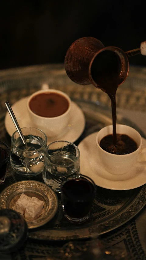 the coffee is being poured into small cups