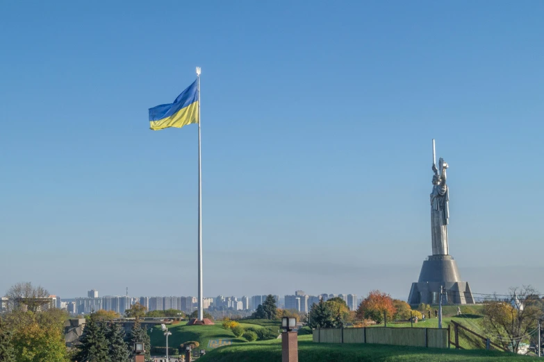 a large white and yellow flag is flying in front of the statue