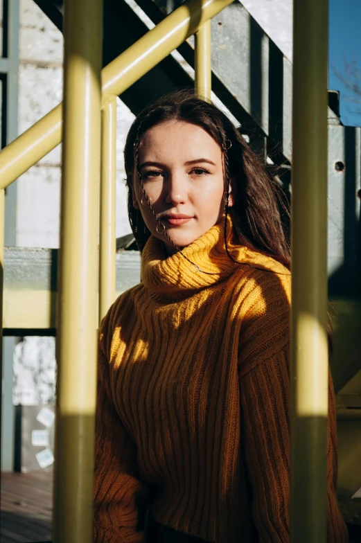 a girl standing in a yellow coat with her hands on her shoulder