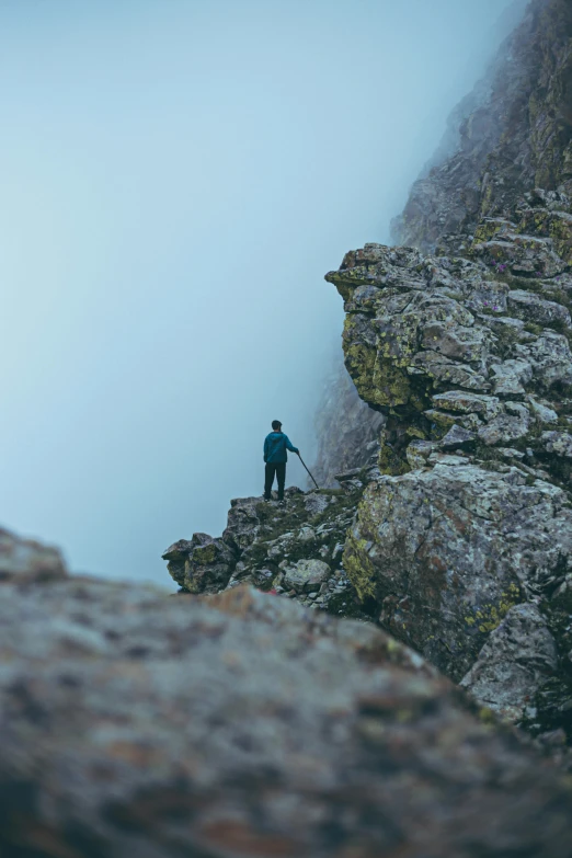 a person stands on the edge of a cliff