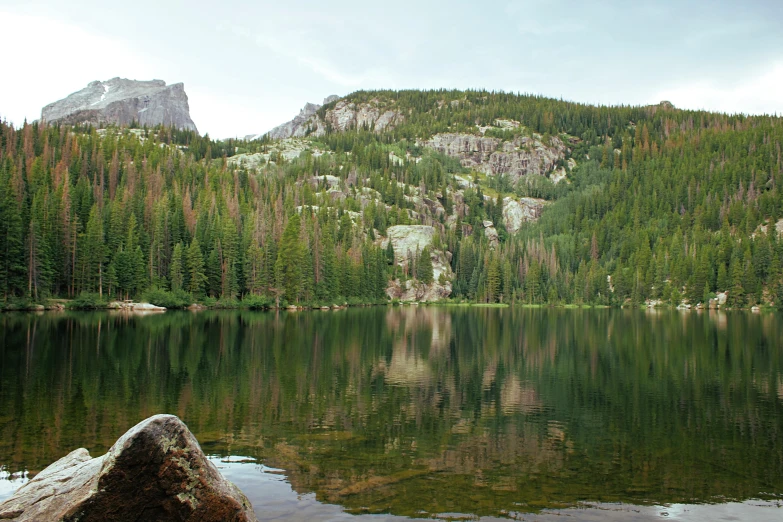 a lake surrounded by trees in front of some mountains