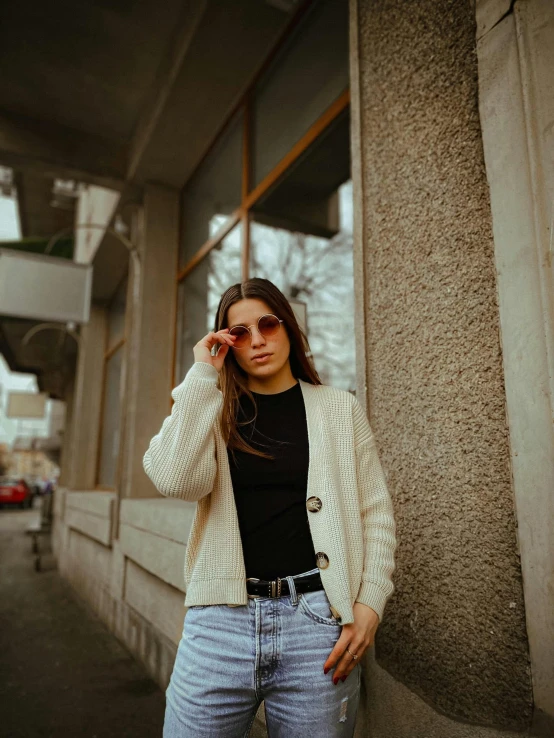 woman in sweater leaning against building while talking on cellphone