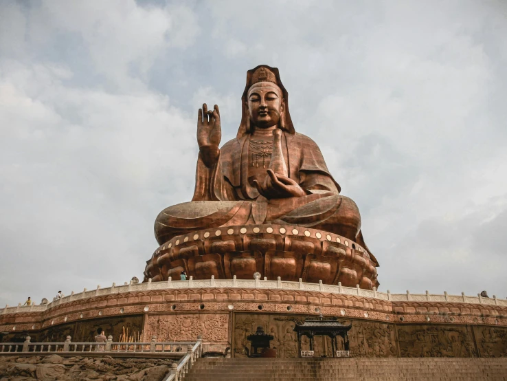 a big buddha statue sitting up against a cloudy sky