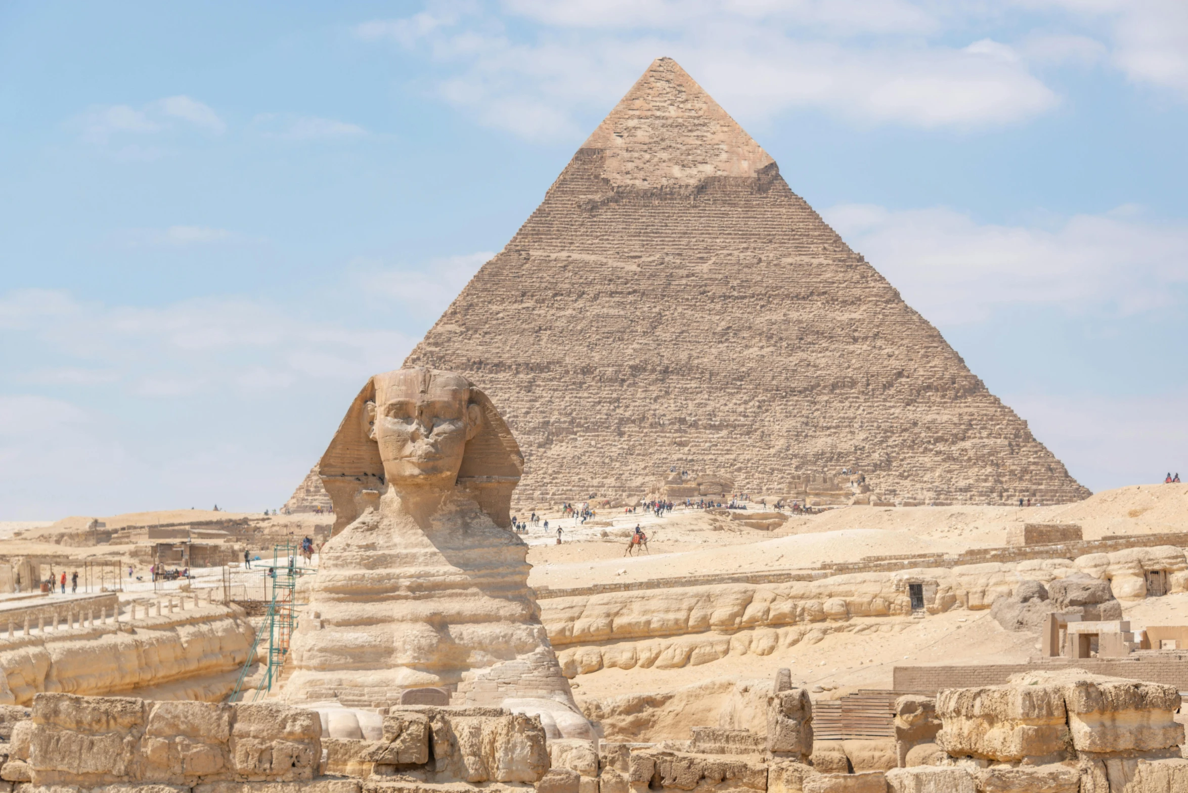 a large sphinx sits in front of a tall pyramid