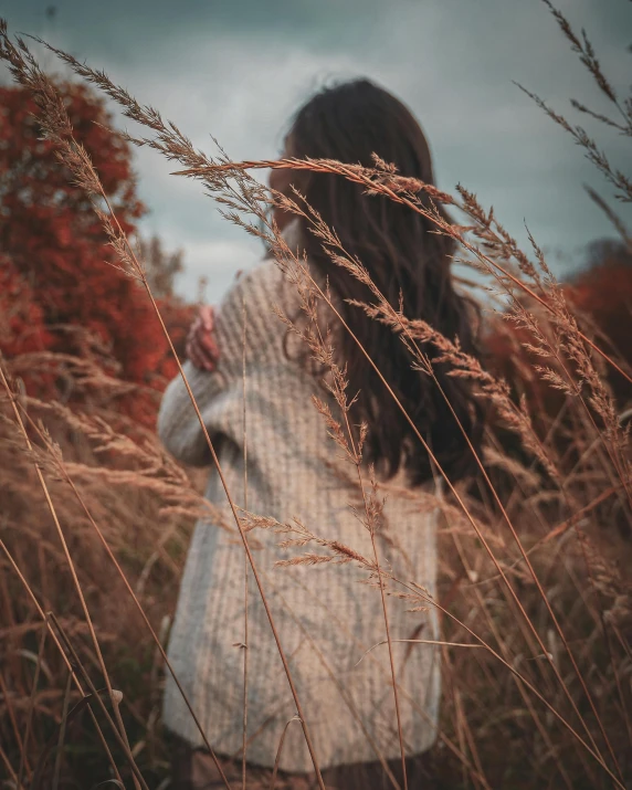 a woman standing in tall brown grass