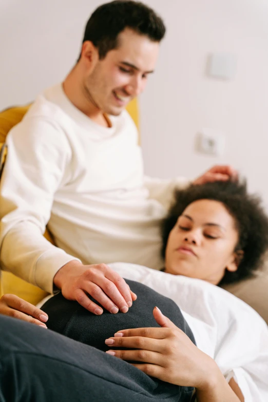 a man sitting next to a women who is laying on the bed