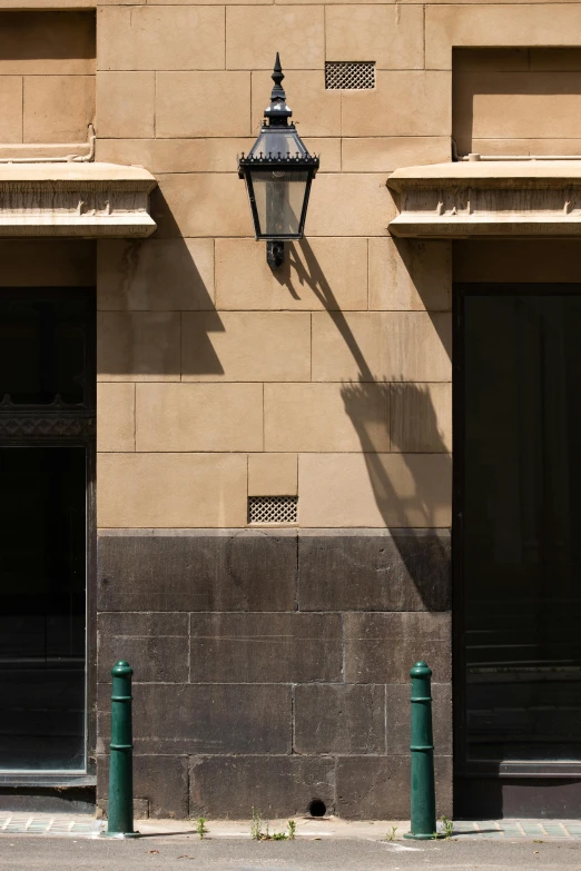 the side of a building with some green metal posts and windows