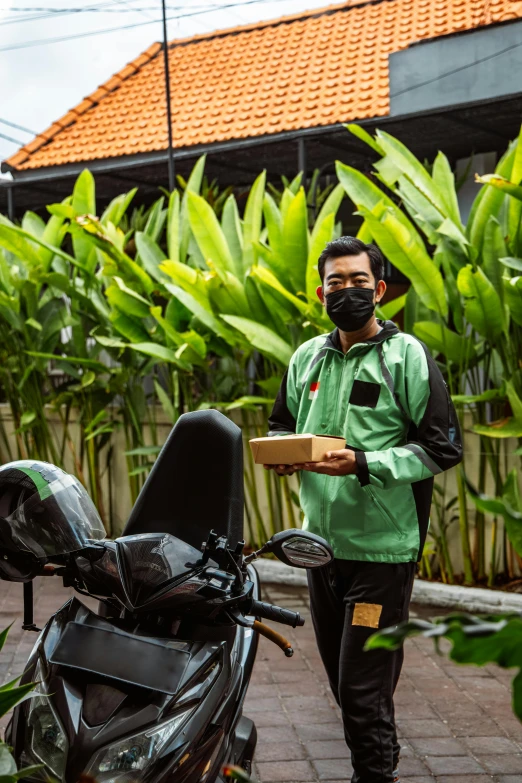 man in black pants and a mask holding a box