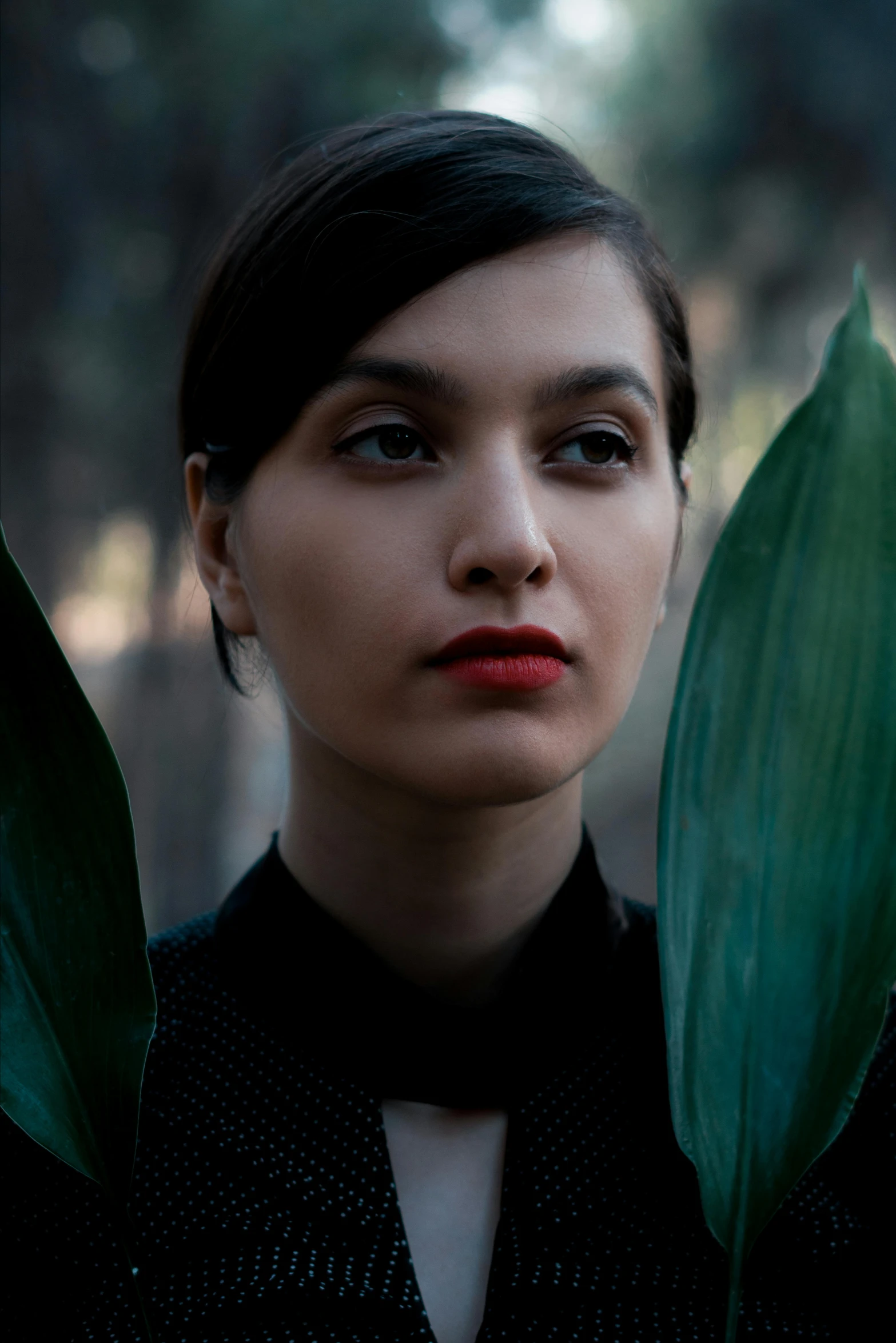 a woman with bangs holding leaves in her hands