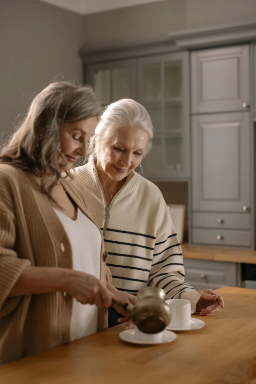 two older women standing next to each other holding cups