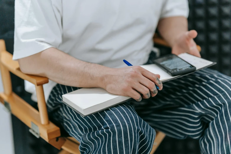 a man sitting down with a book and a laptop