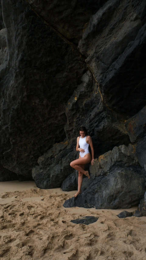 the woman is sitting on rocks near a body of water