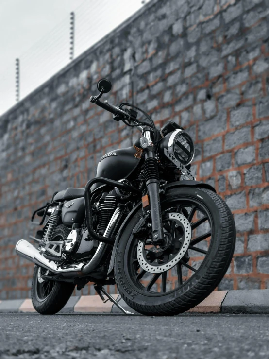 a motorcycle sits on the pavement against a brick wall