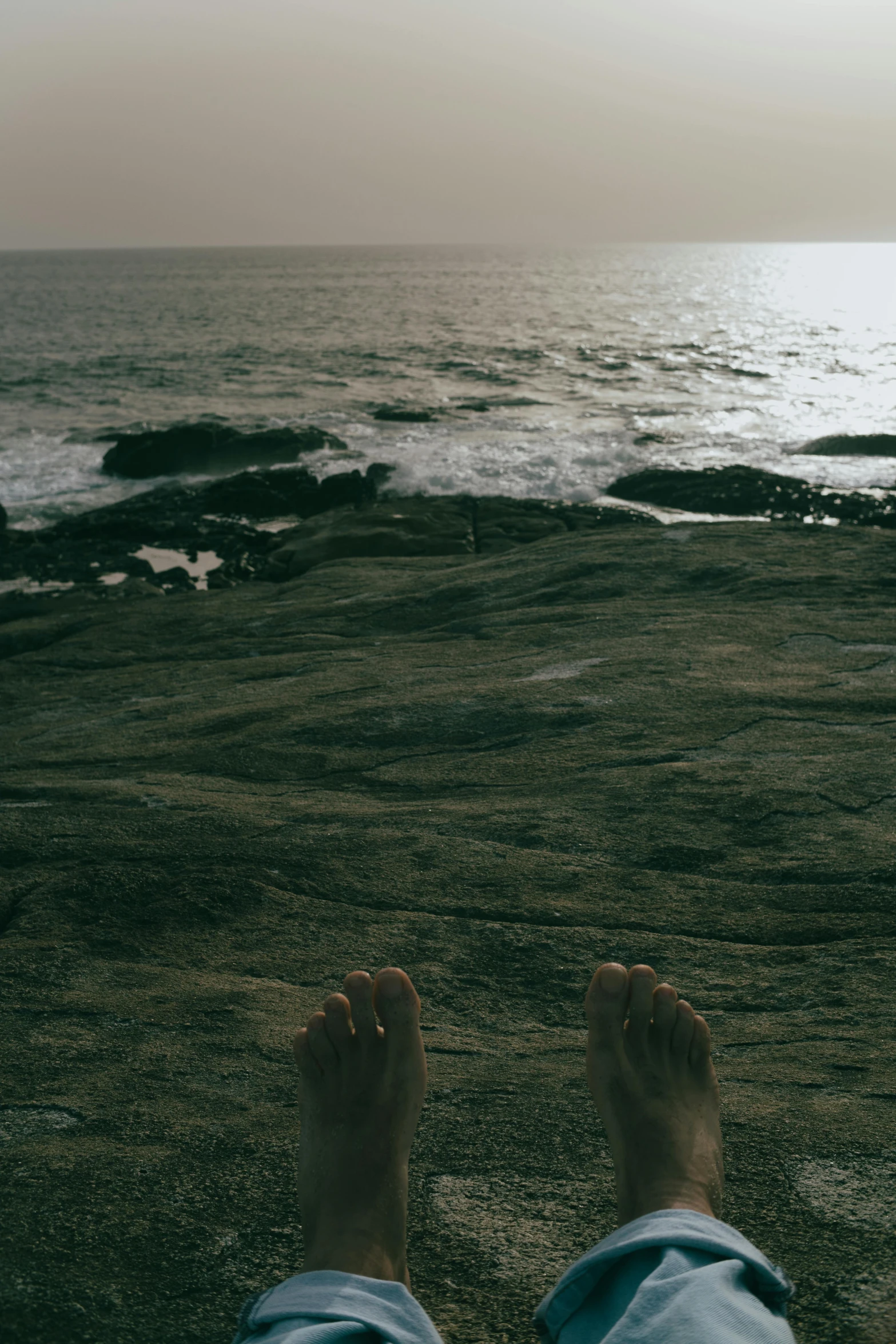 person with feet up near ocean and shoreline