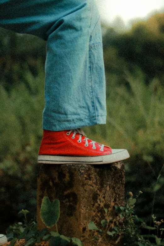 a man in red converses is walking on top of a stump