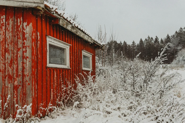 an old red building covered in snow by some trees