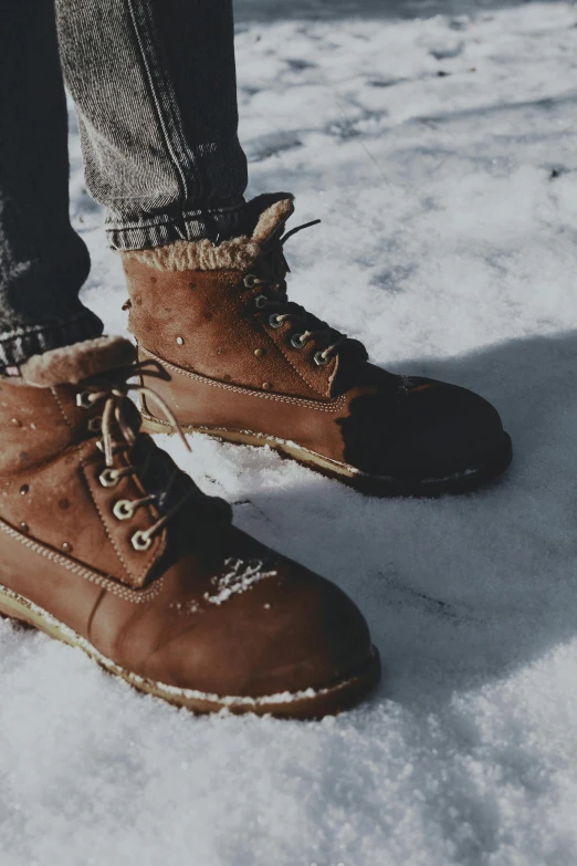 someone is standing outside on the snow wearing their hiking boots